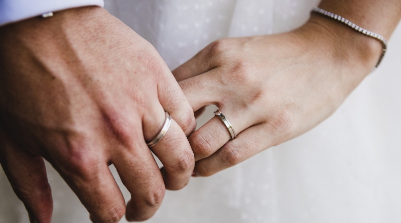 manos con anillos de compromiso representando una boda